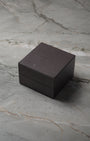 angled overview of the closed, textured black TAG Heuer luxury watch presentation box sitting on a stone studio surface