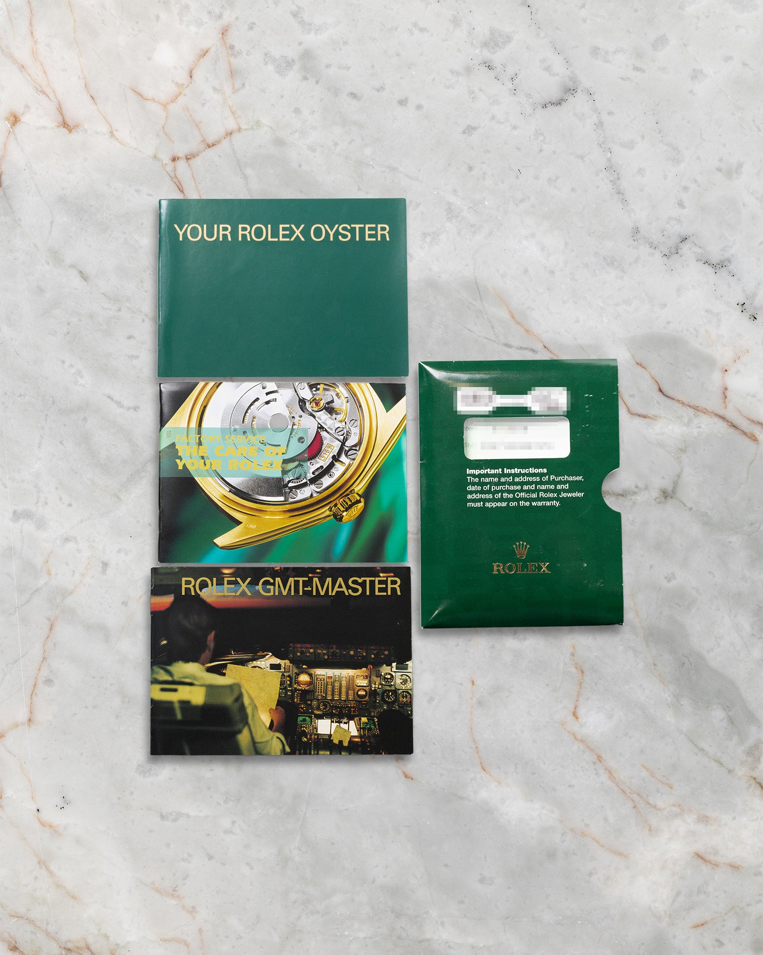 The 2004 pre-owned Rolex GMT-Master II 16713 full set including the original green leather watch box, punched paper warranty certificate, and booklets at Noahs Fine Watches and Jewelry Dallas