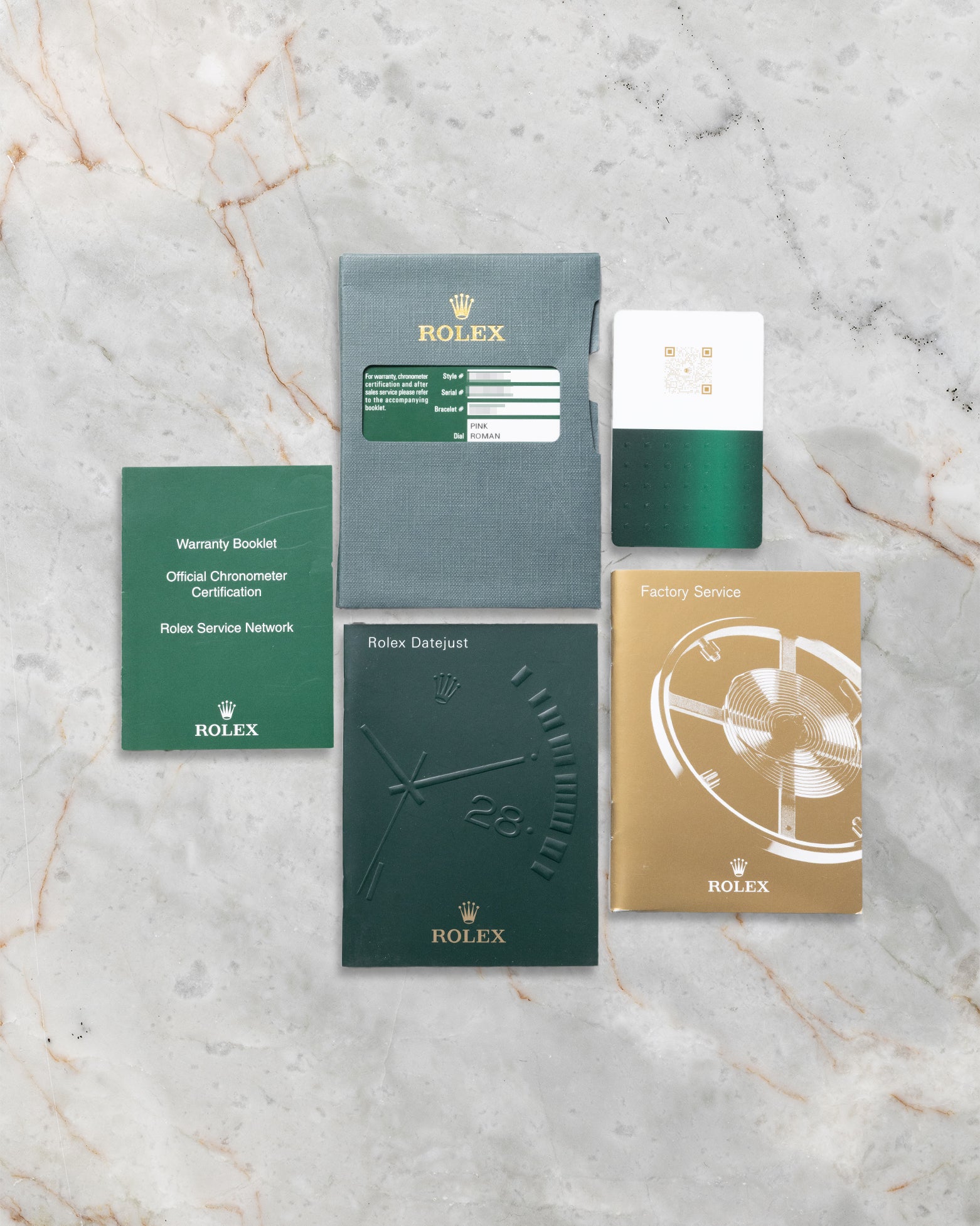 The official Rolex international guarantee card, user manual booklets, and factory papers laid out on a gray marble surface