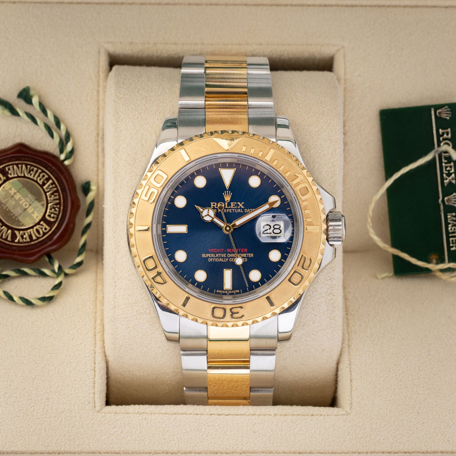 direct frontal portrait of the 2010 two-tone Rolex Yacht-Master 16623 watch with a royal blue dial resting inside its green presentation box wrapper