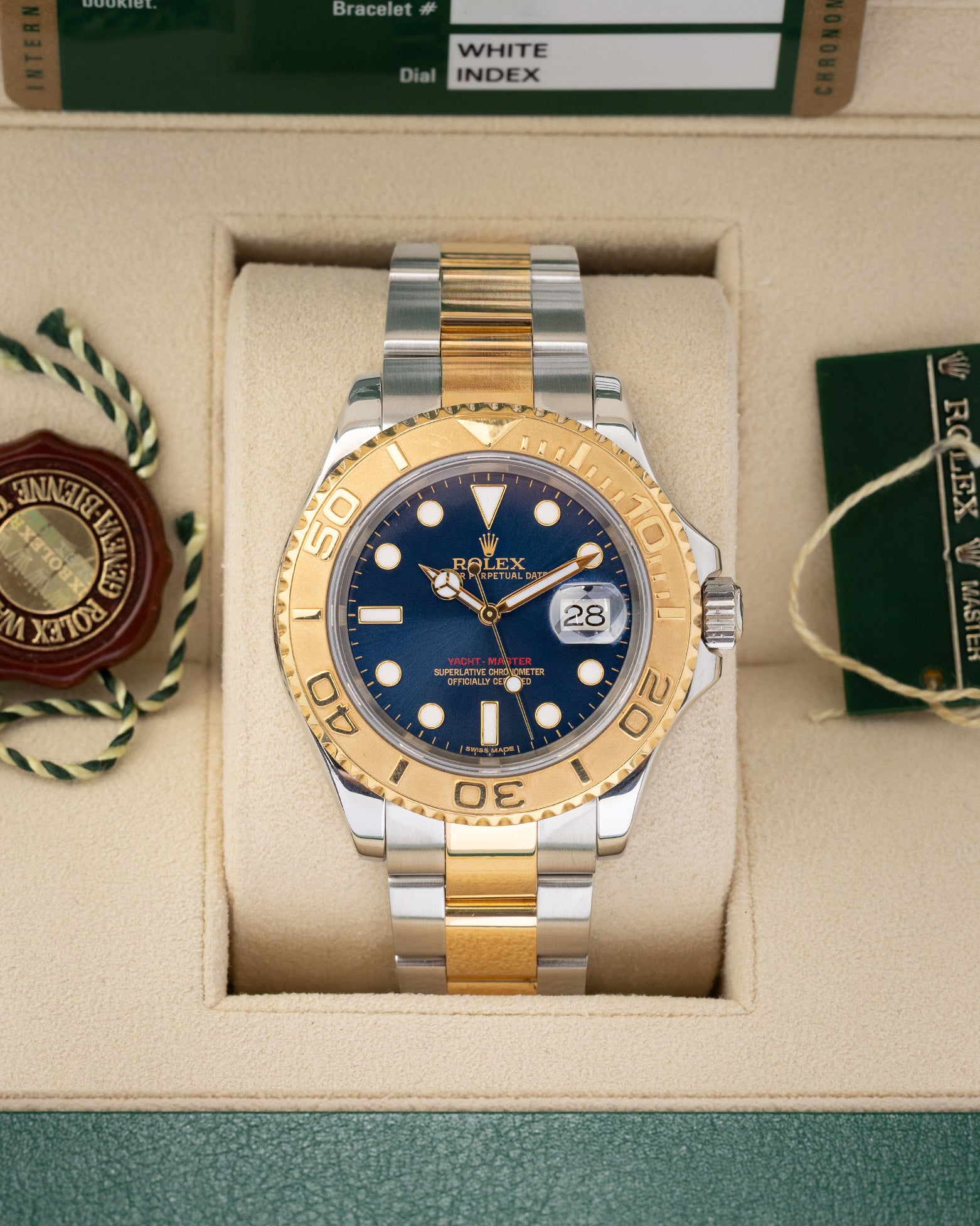 direct frontal portrait of the 2010 two-tone Rolex Yacht-Master 16623 watch with a royal blue dial resting inside its green presentation box wrapper
