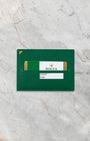 Official green Rolex international guarantee warranty card resting inside its classic green leather document wallet sleeve on marble