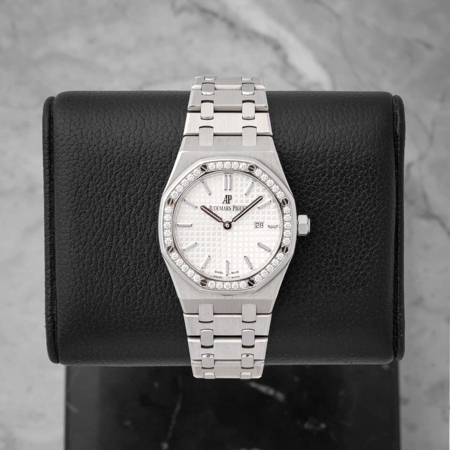 studio front portrait of the 33mm Audemars Piguet Royal Oak 67651ST watch with a diamond bezel and silver Grande Tapisserie dial on a leather block