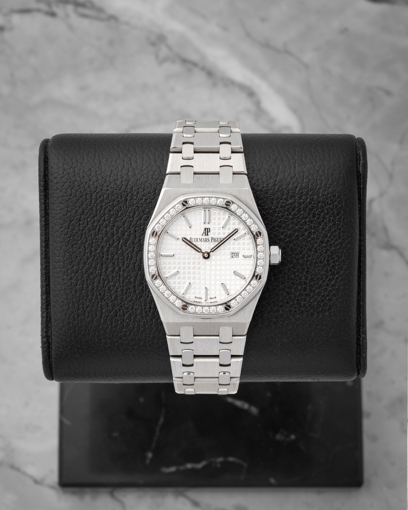 studio front portrait of the 33mm Audemars Piguet Royal Oak 67651ST watch with a diamond bezel and silver Grande Tapisserie dial on a leather block
