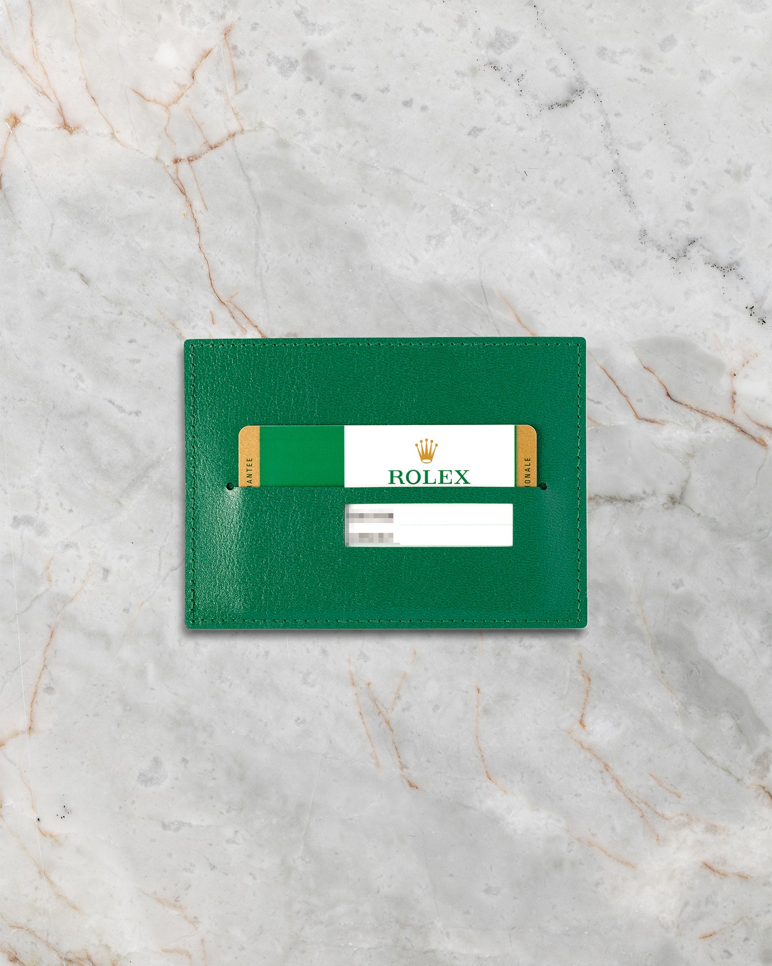 Authentic 2019 Rolex green international guarantee warranty card displayed inside its official green saffiano leather cardholder on a white marble slab