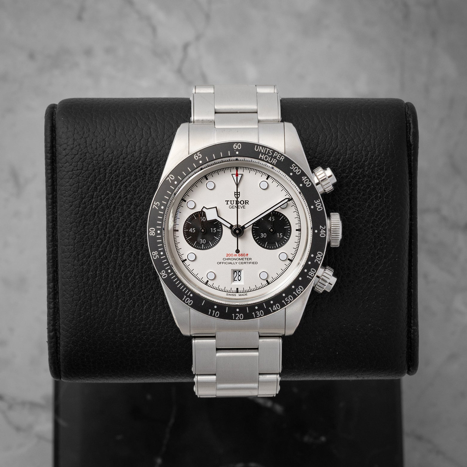 frontal portrait of the 2021 Tudor Black Bay Chrono M79360N watch with a white opaline panda dial on a black leather display mount