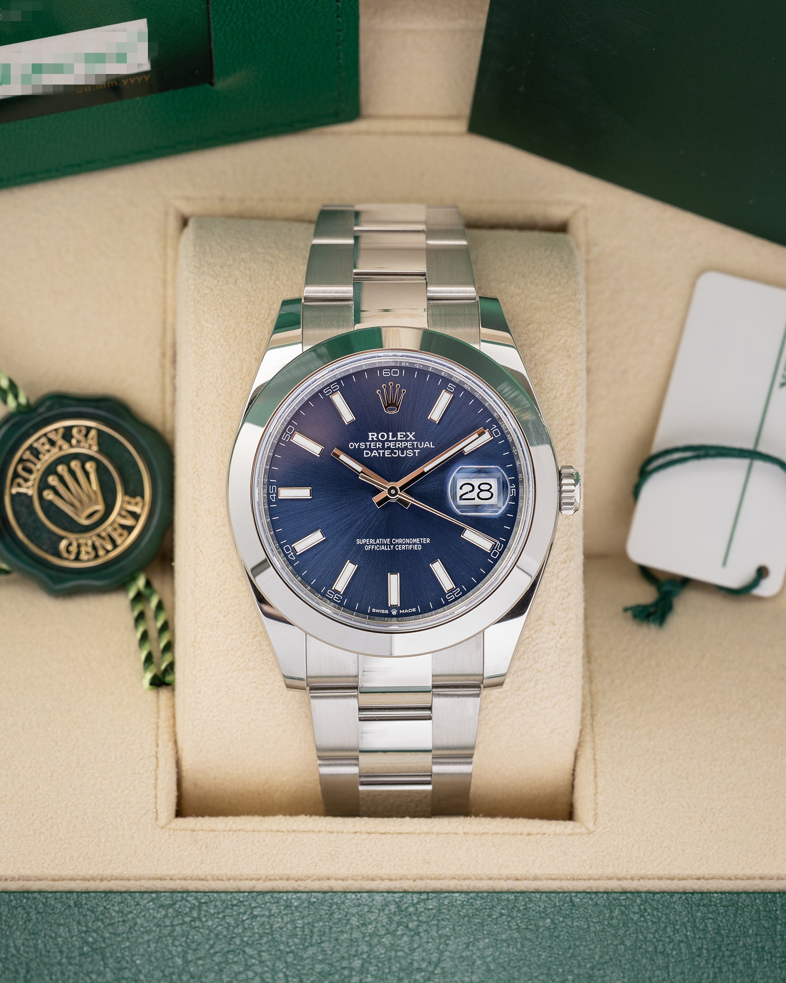 front portrait of a 2024 Rolex Datejust 41 126300 watch with a blue sunray dial and Oyster bracelet resting inside its luxury green presentation box