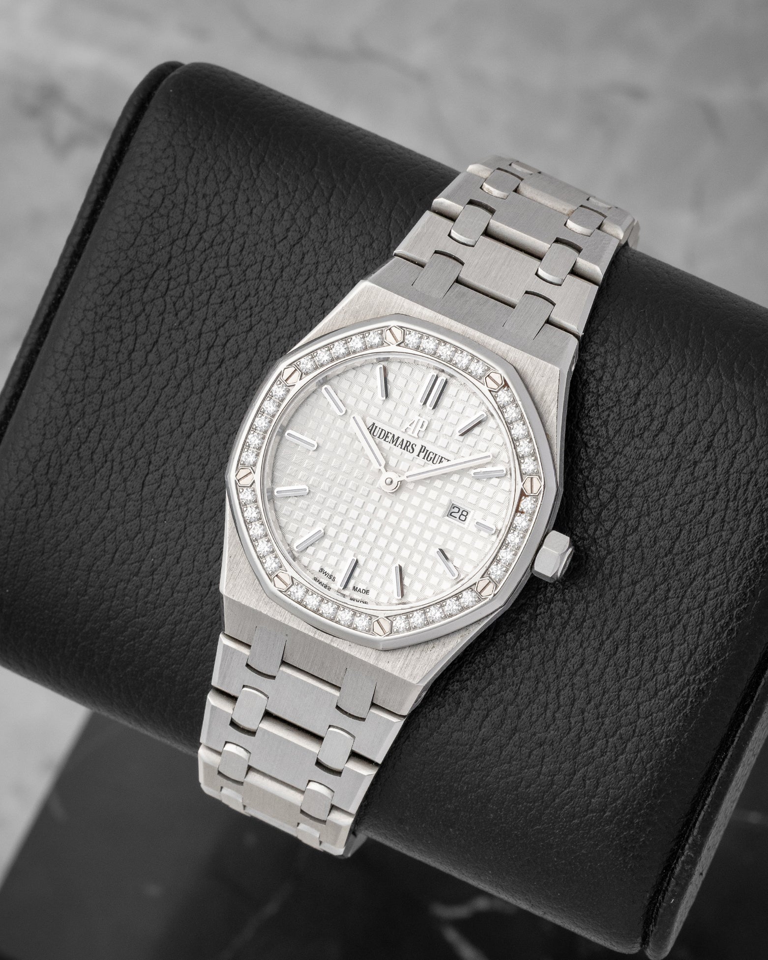 angled top-down studio overview of the stainless steel 33mm Audemars Piguet Royal Oak watch showing its integrated steel bracelet and textured silver dial
