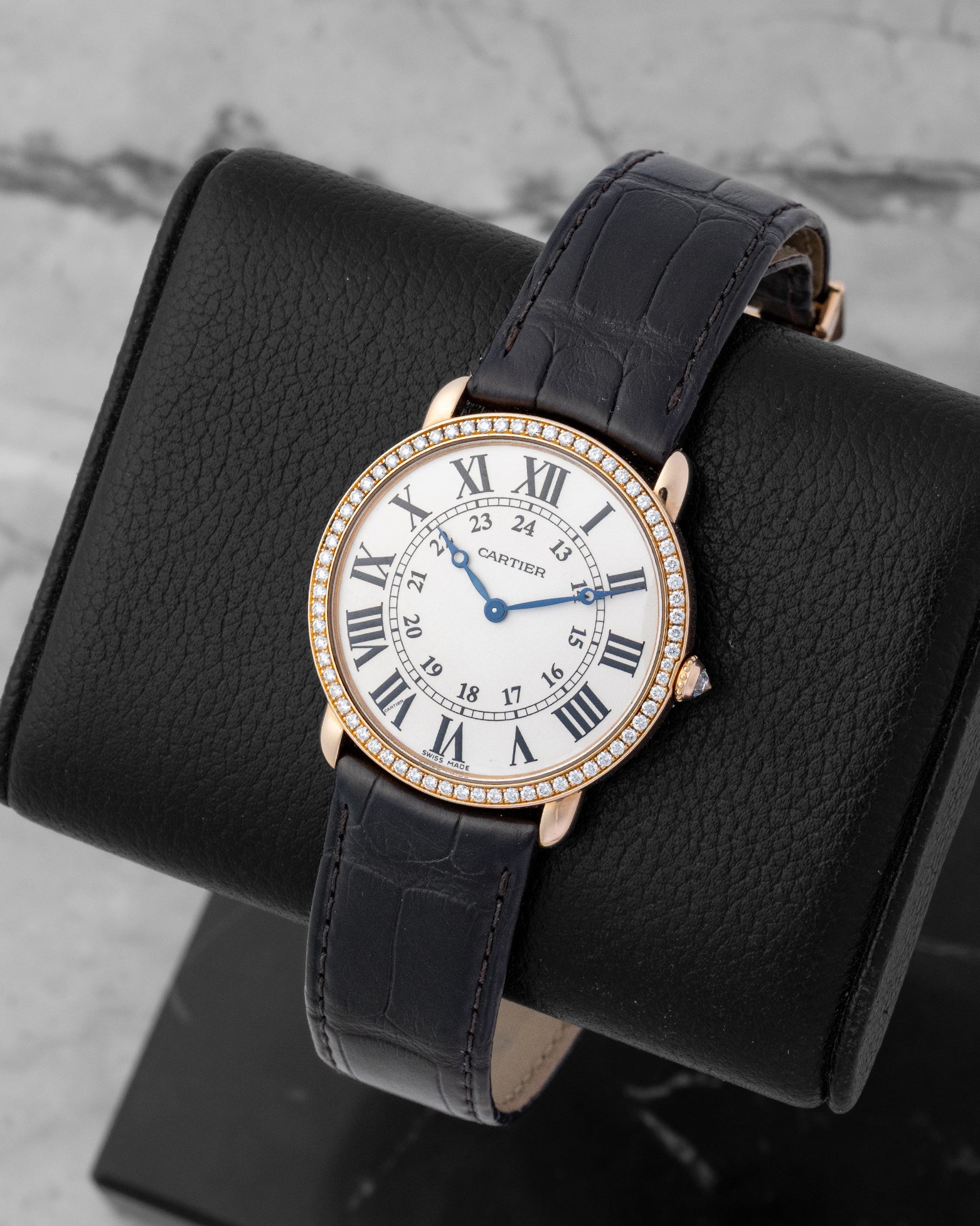 Angled shot of a Cartier Ronde Louis dress watch showcasing the classic black Roman numerals and blue apple-shaped hands