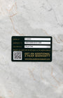 black and green Audemars Piguet international warranty activation card showing the registration barcode flat-laid on a gray marble surface