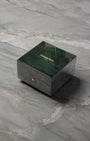 angled overview of the closed, high-gloss green lacquered wooden Audemars Piguet luxury watch box sitting on a stone studio surface.