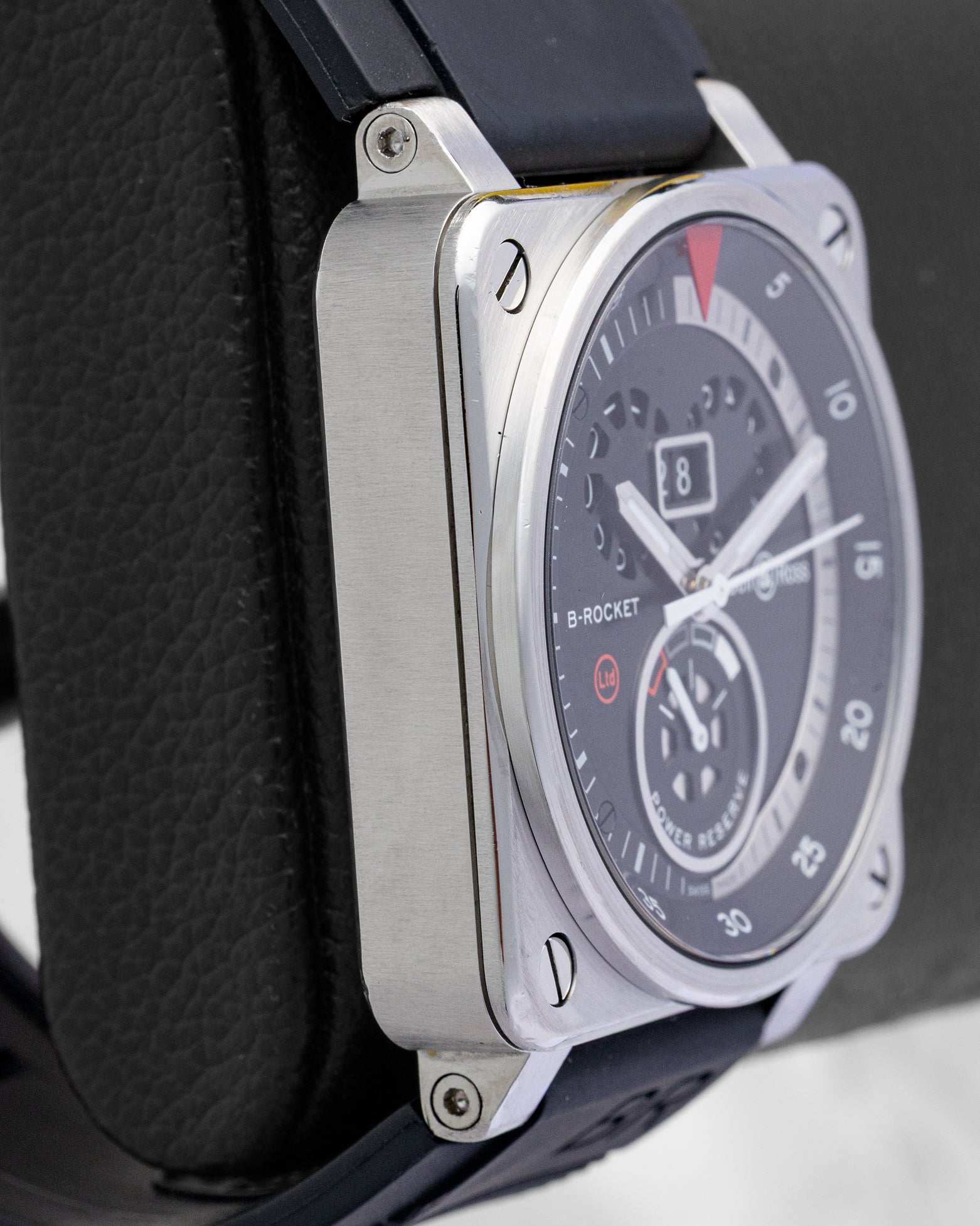 Left-side case profile view of a pre-owned 42mm square steel Bell and Ross B-Rocket watch resting on a black leather presentation block