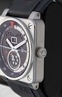 Satin-polished stainless steel square case profile view showing the knurled winding crown and industrial bezel screws on a Bell and Ross watch