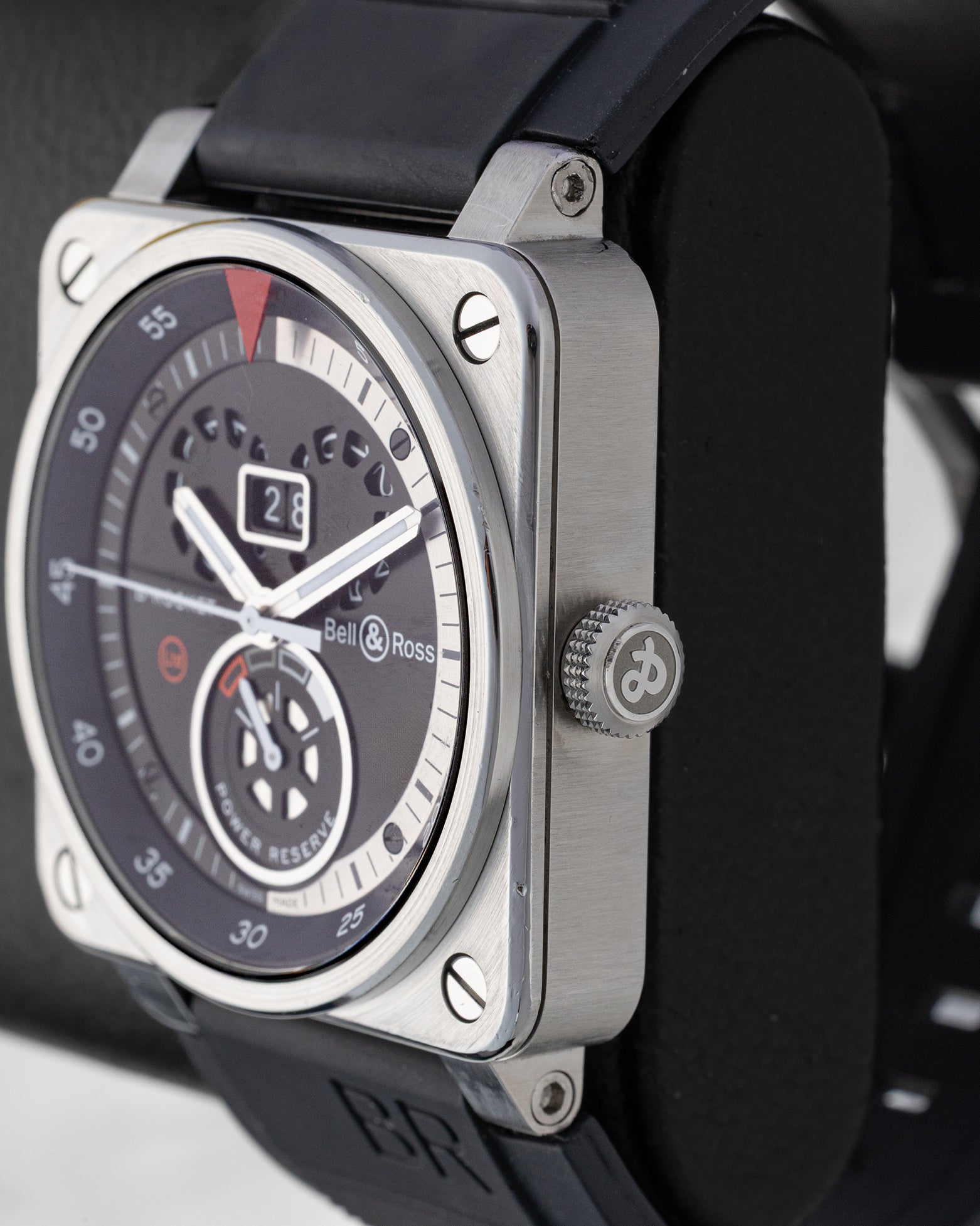 Satin-polished stainless steel square case profile view showing the knurled winding crown and industrial bezel screws on a Bell and Ross watch