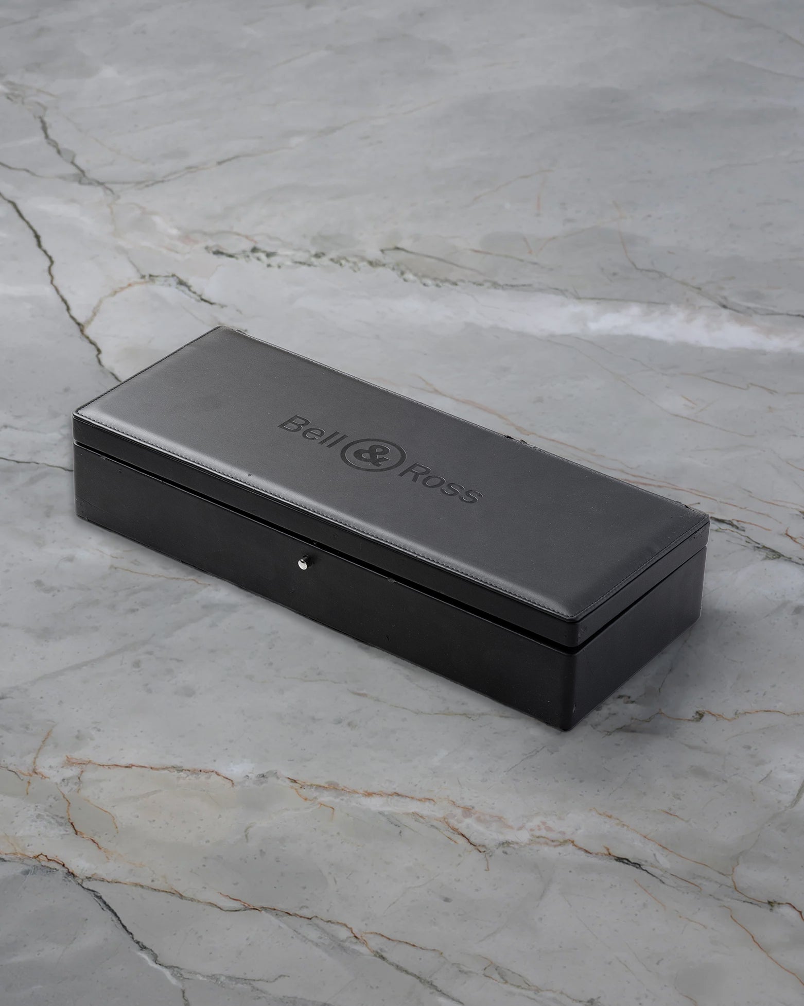 Official sleek black rectangular Bell and Ross presentation watch box debossed with the brand logo sitting on marble