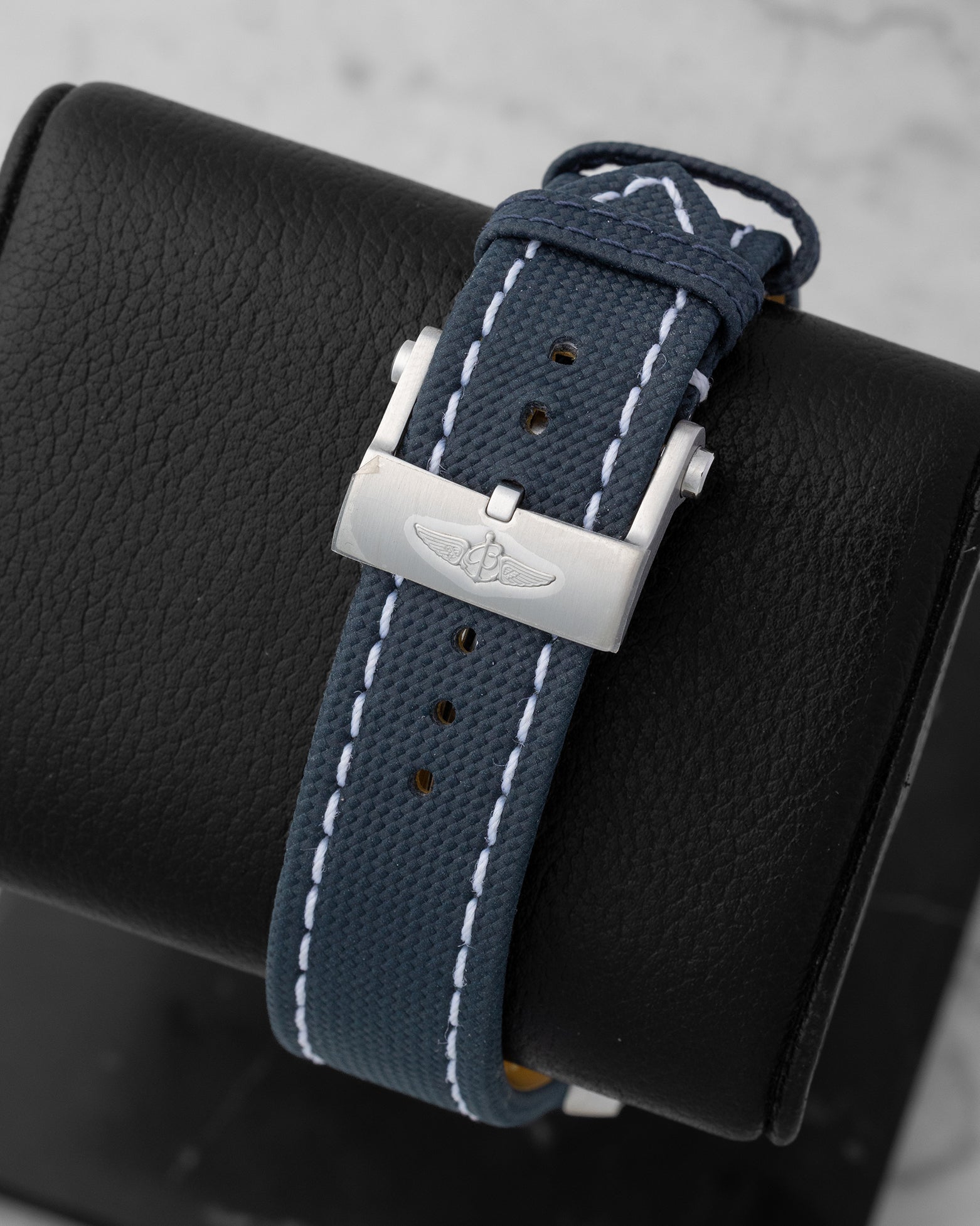 Back view showing the blue leather military strap with stainless steel winged logo tang buckle on a Breitling Avenger GMT A24315101C1X1