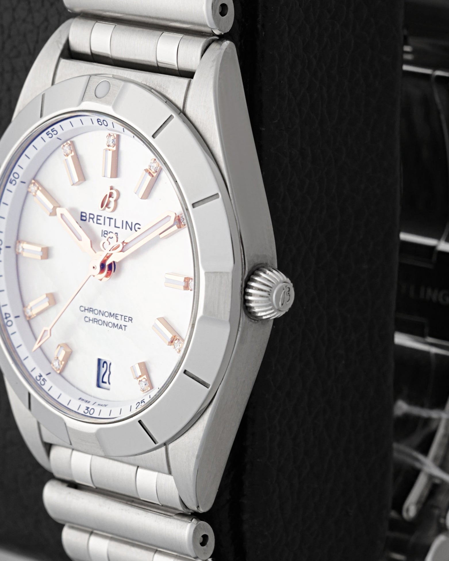 Close-up right profile view of the slim watch head focusing on the classic satin-brushed fixed bezel with engraved rider tabs and the fluted push-pull winding crown