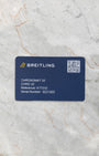 A top-down flat lay view of the official navy blue Breitling electronic warranty smart card showing the printed reference A77310 and a scannable registration QR code