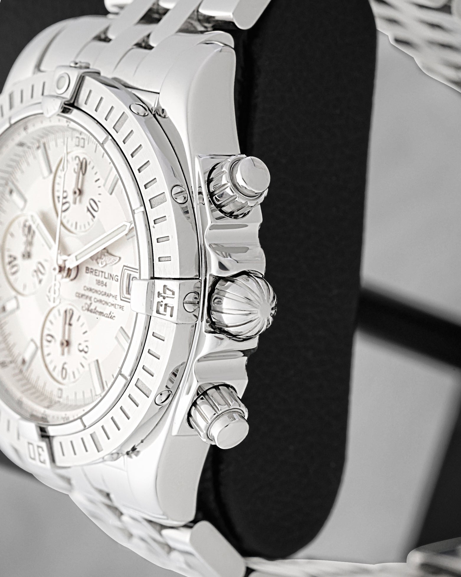 Close-up side view of the screw-down crown, chronograph pushers, and rider tab bezel on Breitling Chronomat Evolution A13356