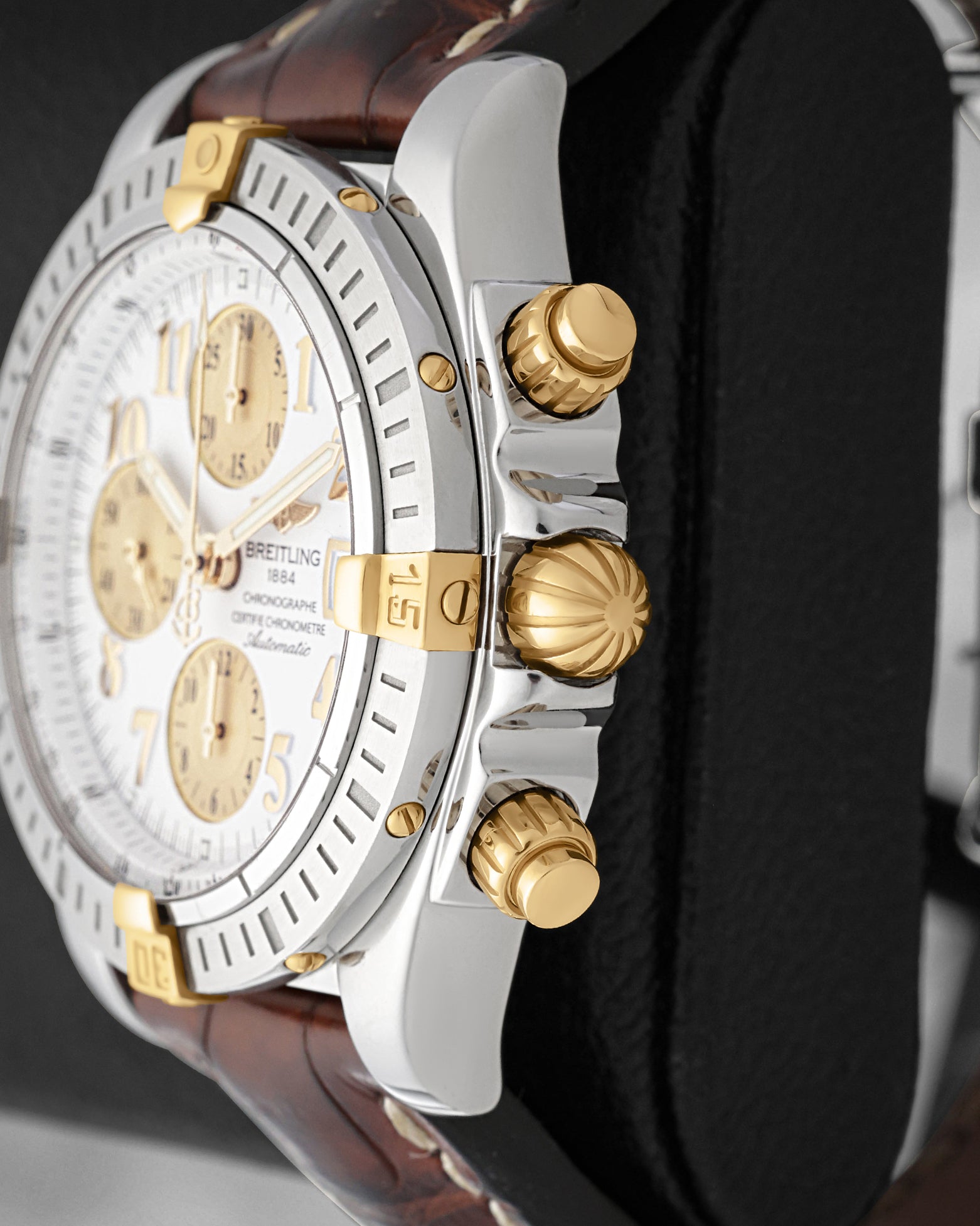 close up of 18k yellow gold screw-down onion crown and chronograph pushers on Breitling Chronomat Evolution B13356