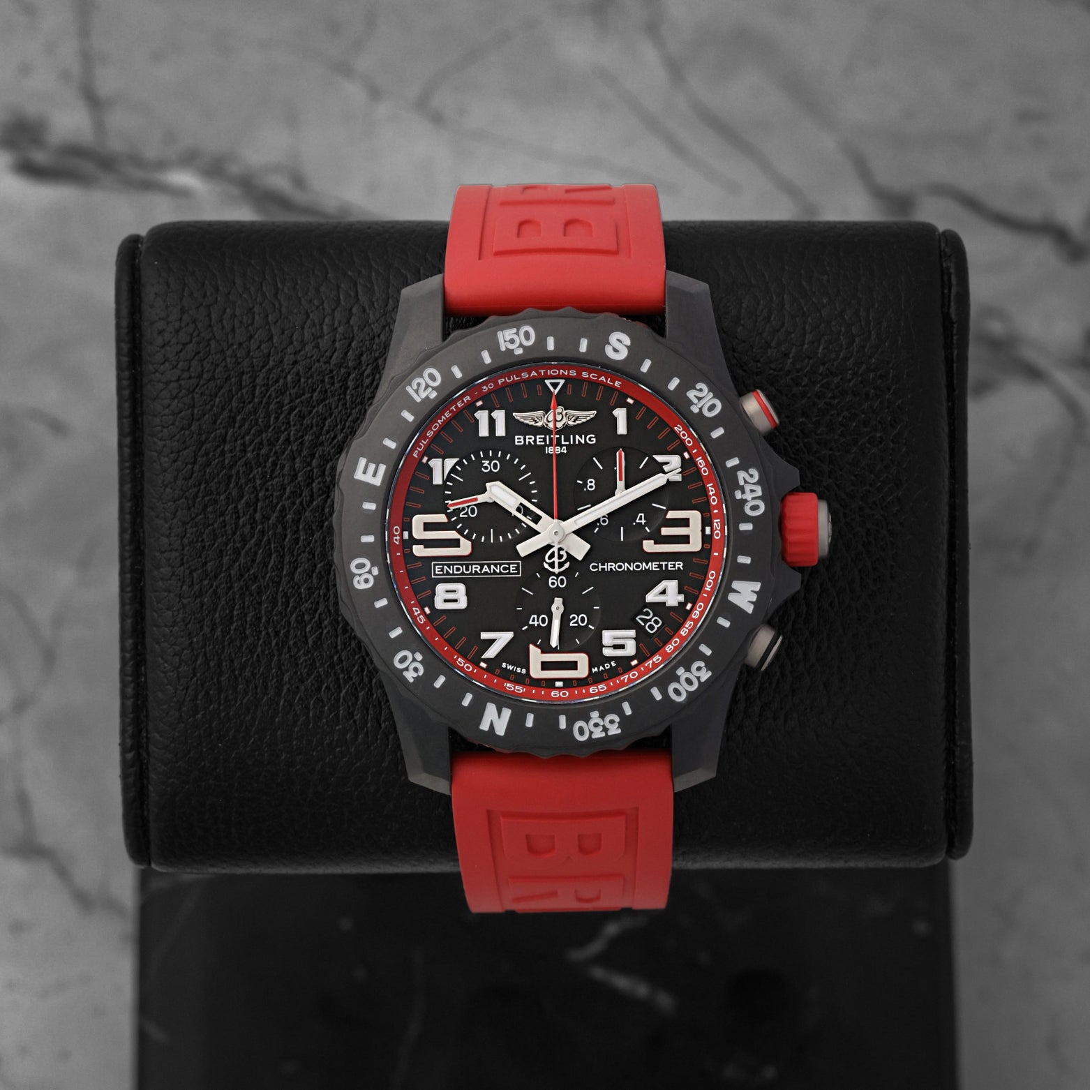 Front portrait of a pre-owned Breitling Endurance Pro 44 Ref X82310D91B1S1 featuring a black Breitlight case and red rubber strap, available at Noahs Fine Watches and Jewelry Dallas