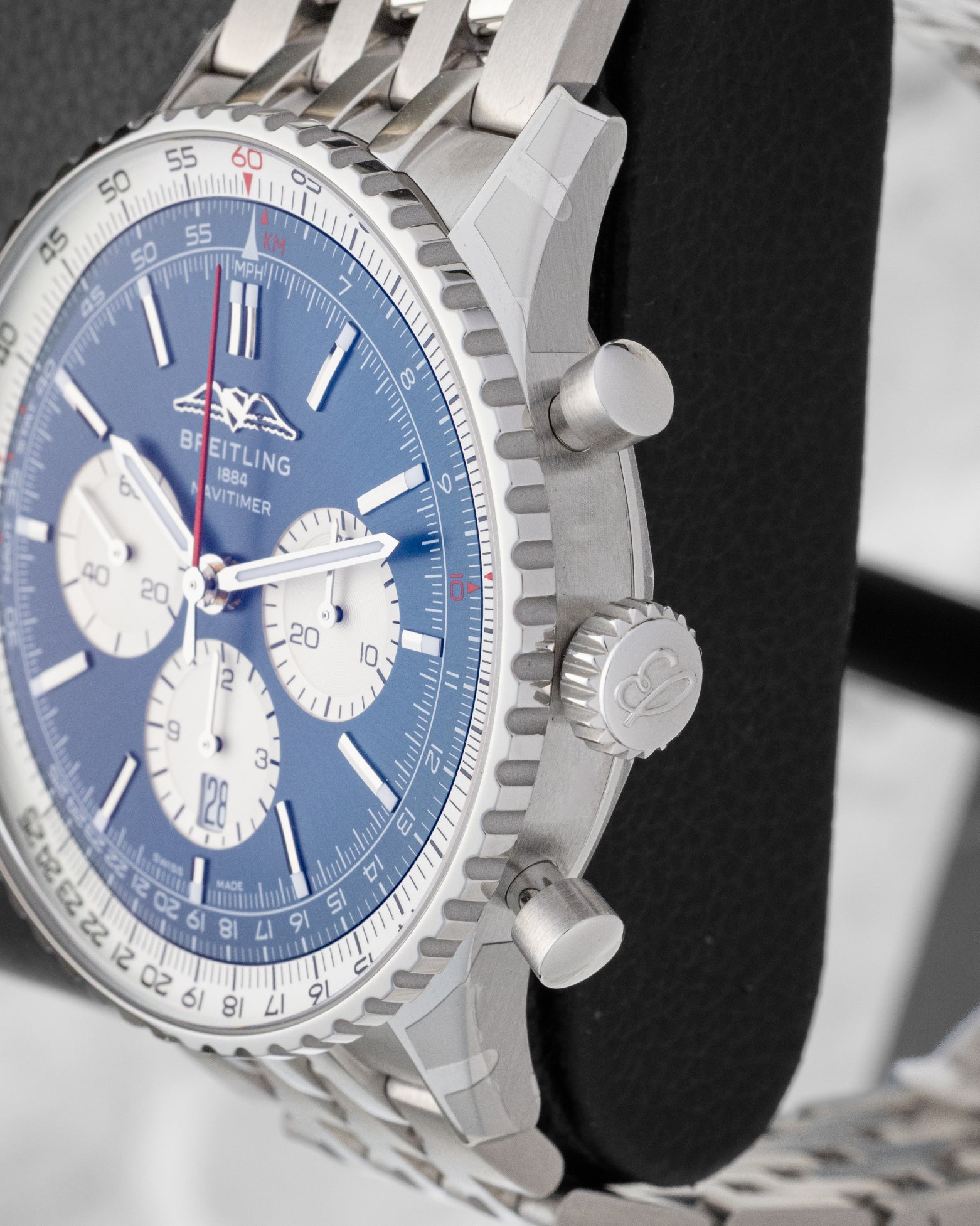 Side profile view of the stainless steel case showing the fluted slide rule bezel, main crown, and piston chronograph pushers
