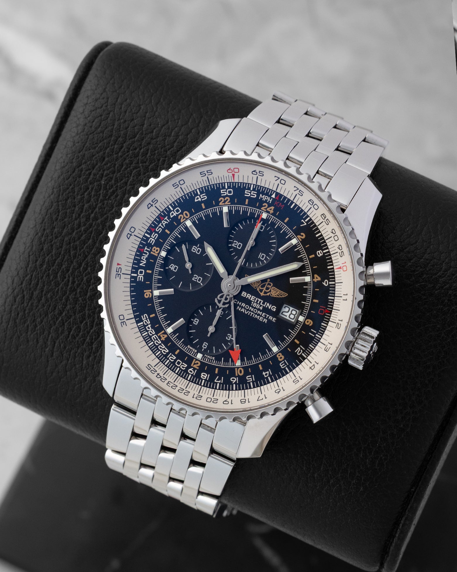 Angled front view of a preowned Breitling Navitimer World A2432212 featuring a black dial, red-tipped GMT hand, sub-dials, and bidirectional slide rule bezel