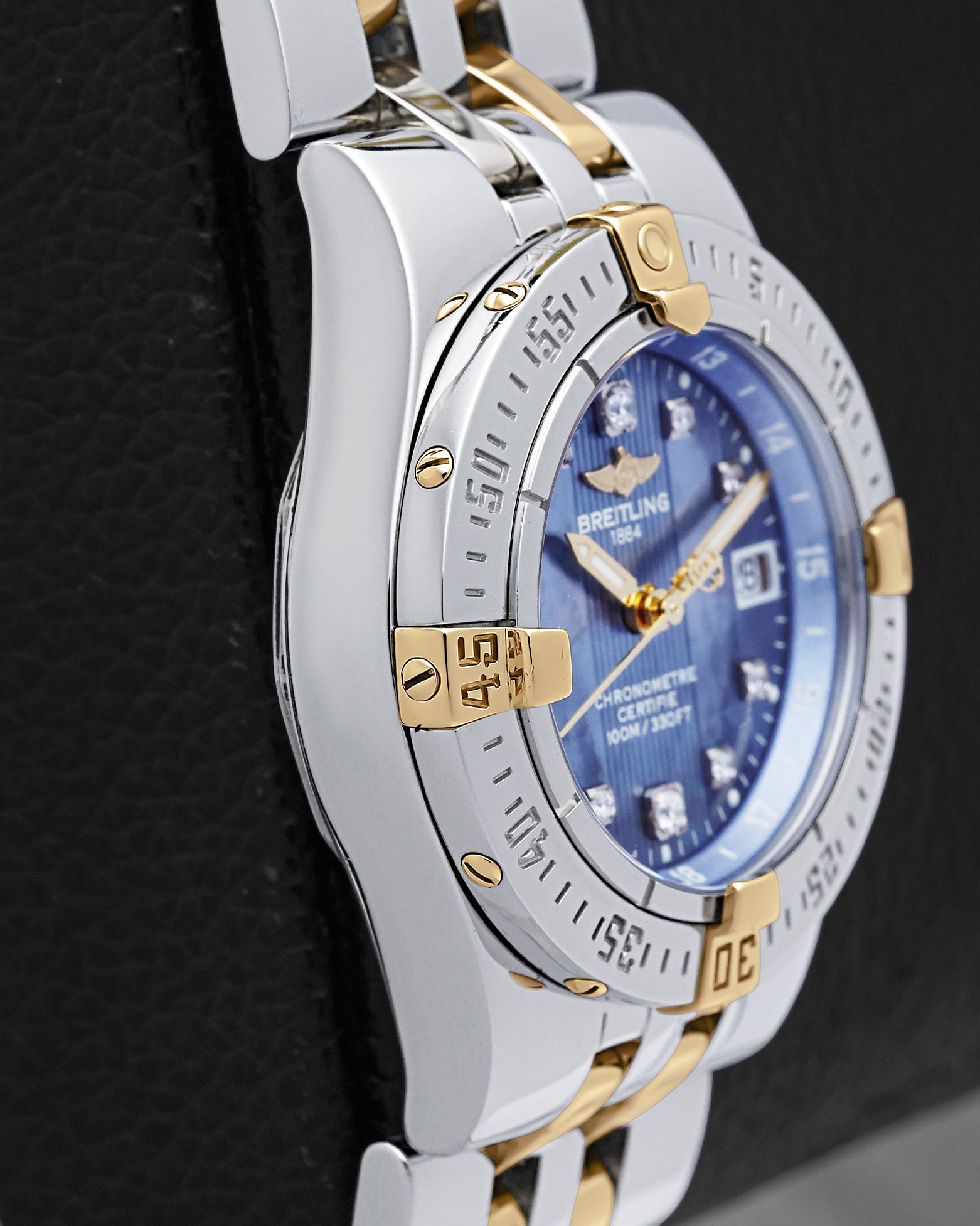 left-side case profile view of a pre-owned steel and 18k yellow gold 30mm ladies Breitling sports watch case resting on a presentation block