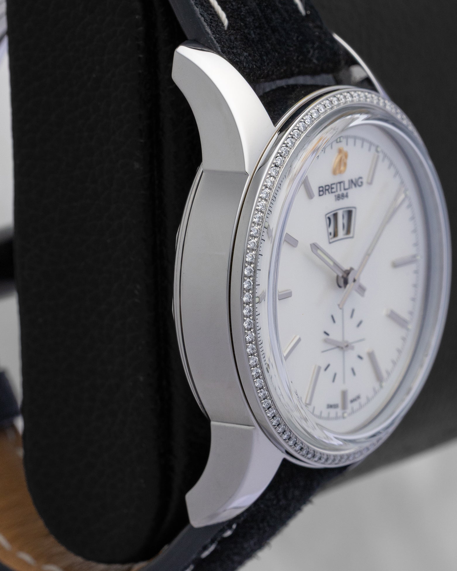 Polished left side profile of the 38mm stainless steel case on a classic Breitling Transocean chronometer watch resting on a leather display cushion