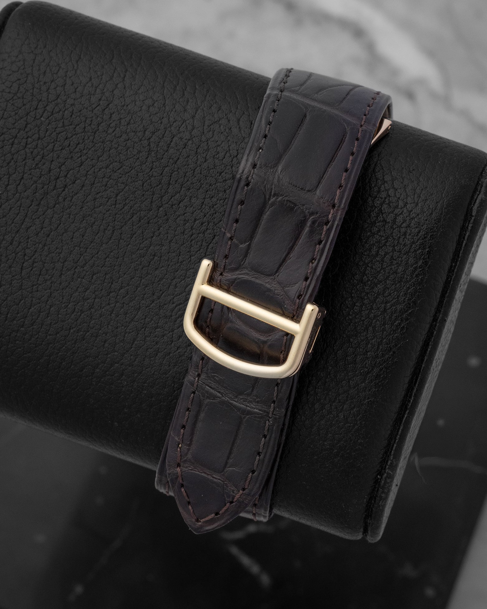 Dark purple alligator leather strap paired with a 18k yellow gold folding deployment buckle on a Cartier watch