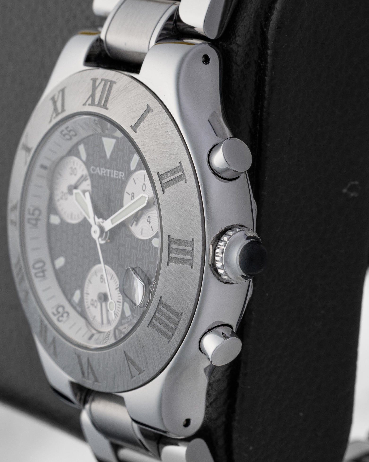 Macro case profile view showing the iconic crown guard profile with integrated white cabochon style detailing and polished steel chronograph push-buttons