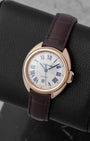 Angled view of a women's Clé de Cartier rose gold watch highlighting the fluid curved case and brown leather strap
