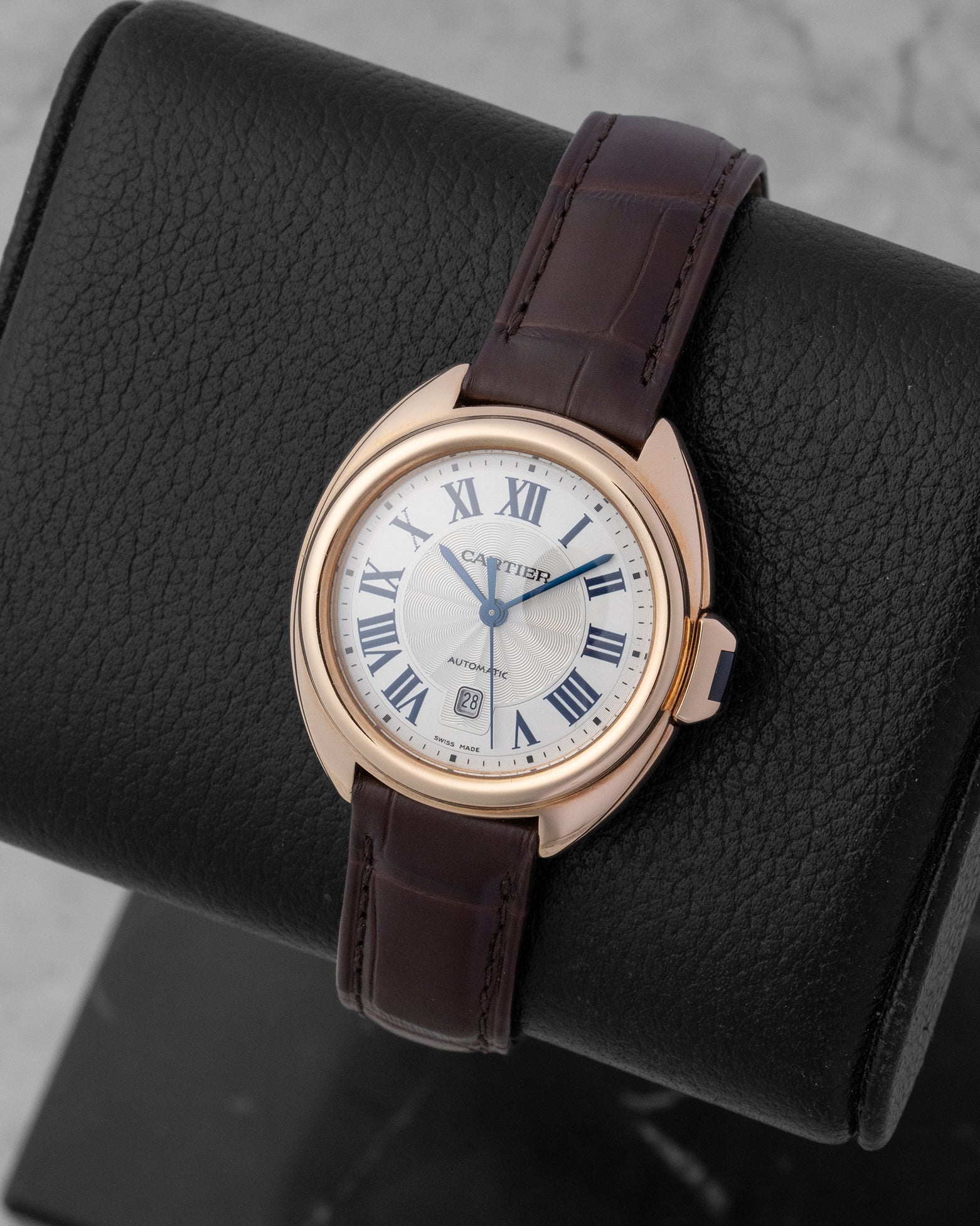 Angled view of a women's Clé de Cartier rose gold watch highlighting the fluid curved case and brown leather strap