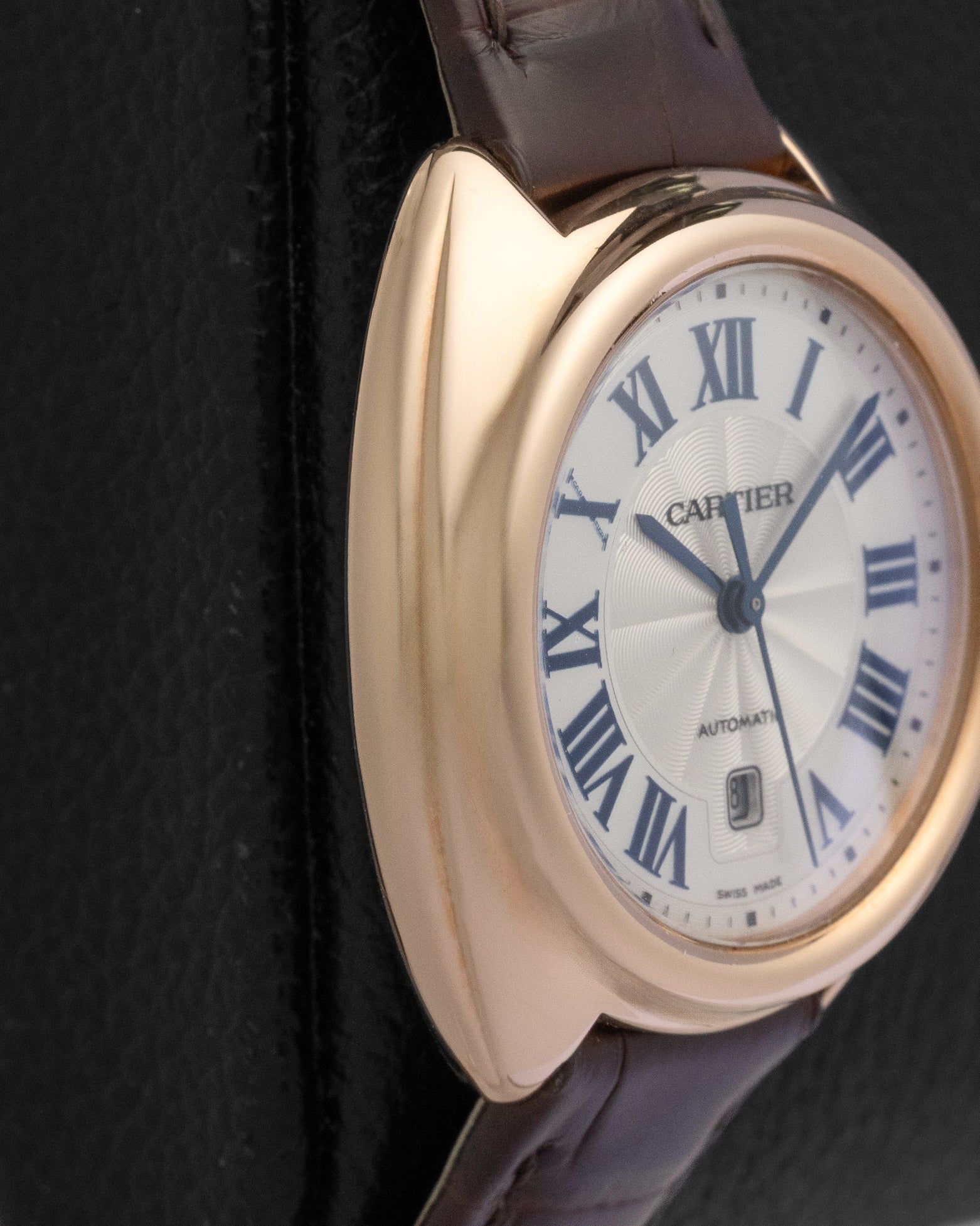 Macro close-up of a Clé de Cartier watch face with a sunray guilloche texture and blued-steel sword hands