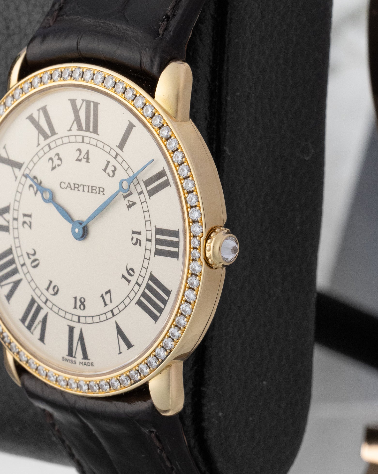 Close-up side profile of the yellow gold watch case highlighting the circular-grained crown set with a diamond cabochon