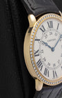 Macro close-up of a silver grained Cartier dial, showcasing the crisp black Roman numerals and blued-steel apple-shaped hands
