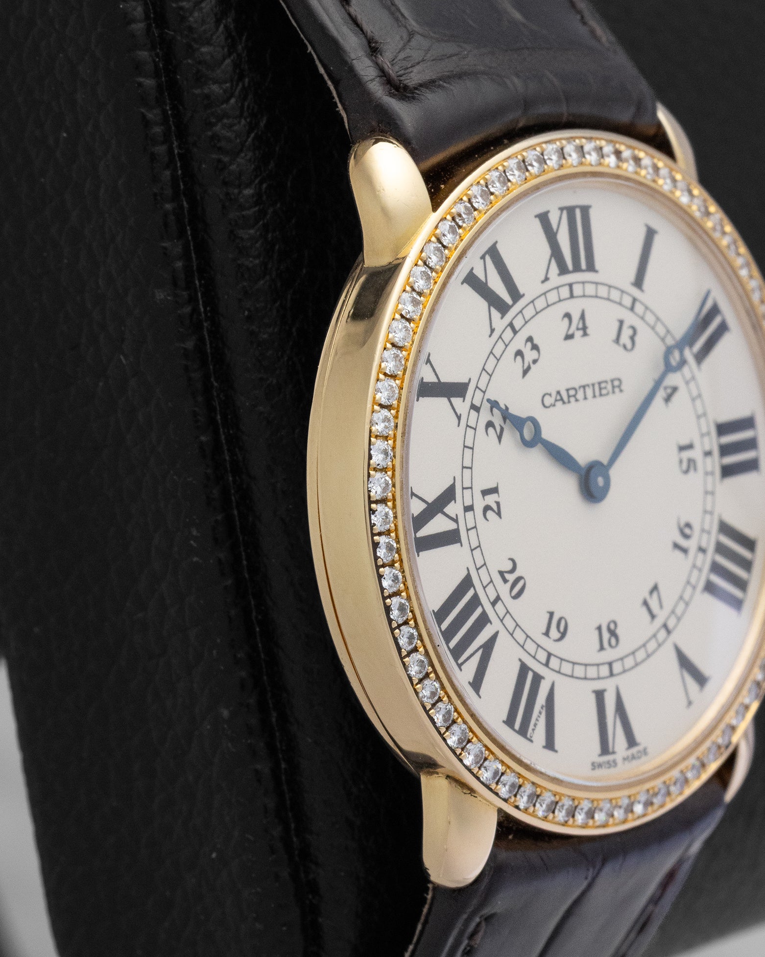 Macro close-up of a silver grained Cartier dial, showcasing the crisp black Roman numerals and blued-steel apple-shaped hands