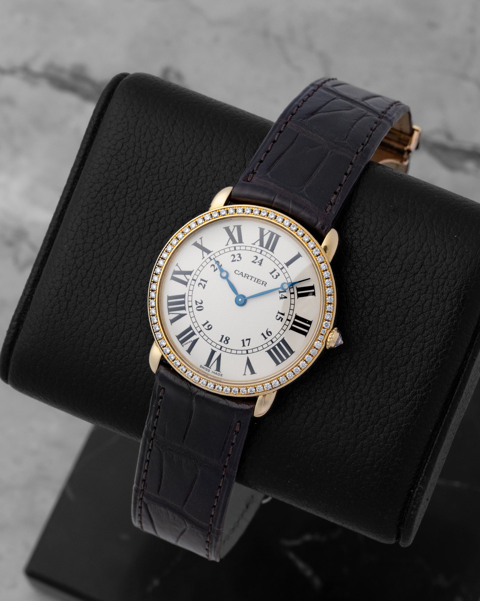 Angled shot of a Cartier Ronde Louis yellow gold watch, showing the dark purple alligator leather strap and diamond bezel details