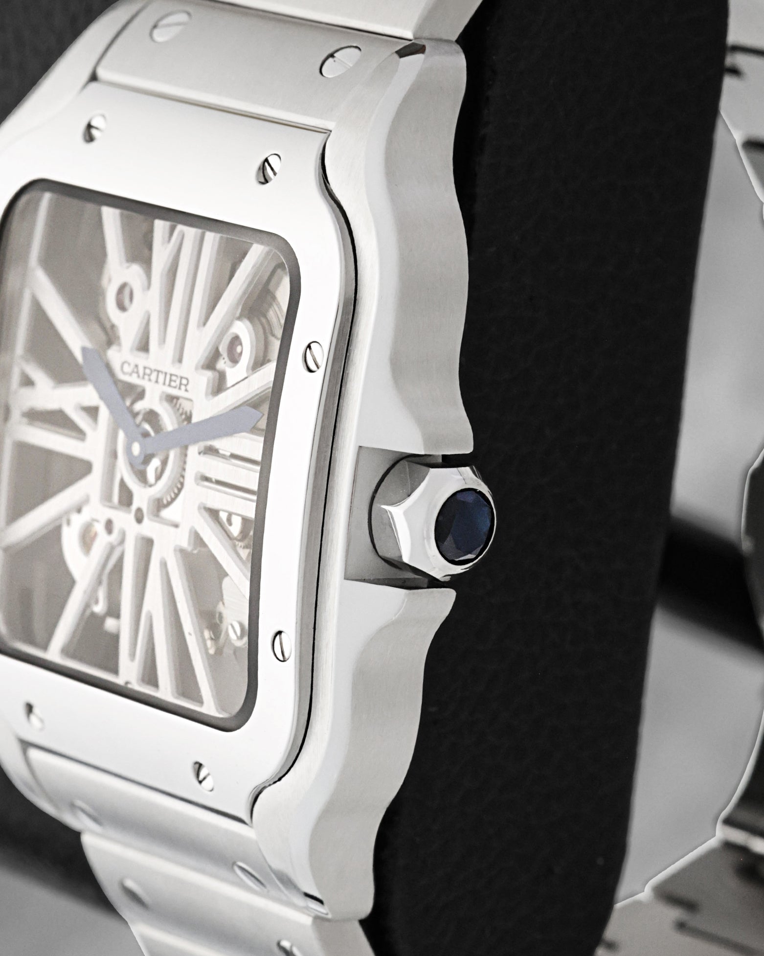 Close-up of the sapphire-set heptagonal crown and stainless steel case edge on a Cartier Santos Skeleton WHSA0015