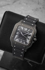 Angled view of pre-owned Cartier Santos de Cartier WSSA0039 featuring a black ADLC case, black dial, and luminous sword hands