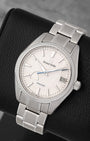 A high-angle three-quarter portrait of the 41mm Grand Seiko Snowflake showing the asymmetric power reserve indicator indicator resting on a black leather cushion