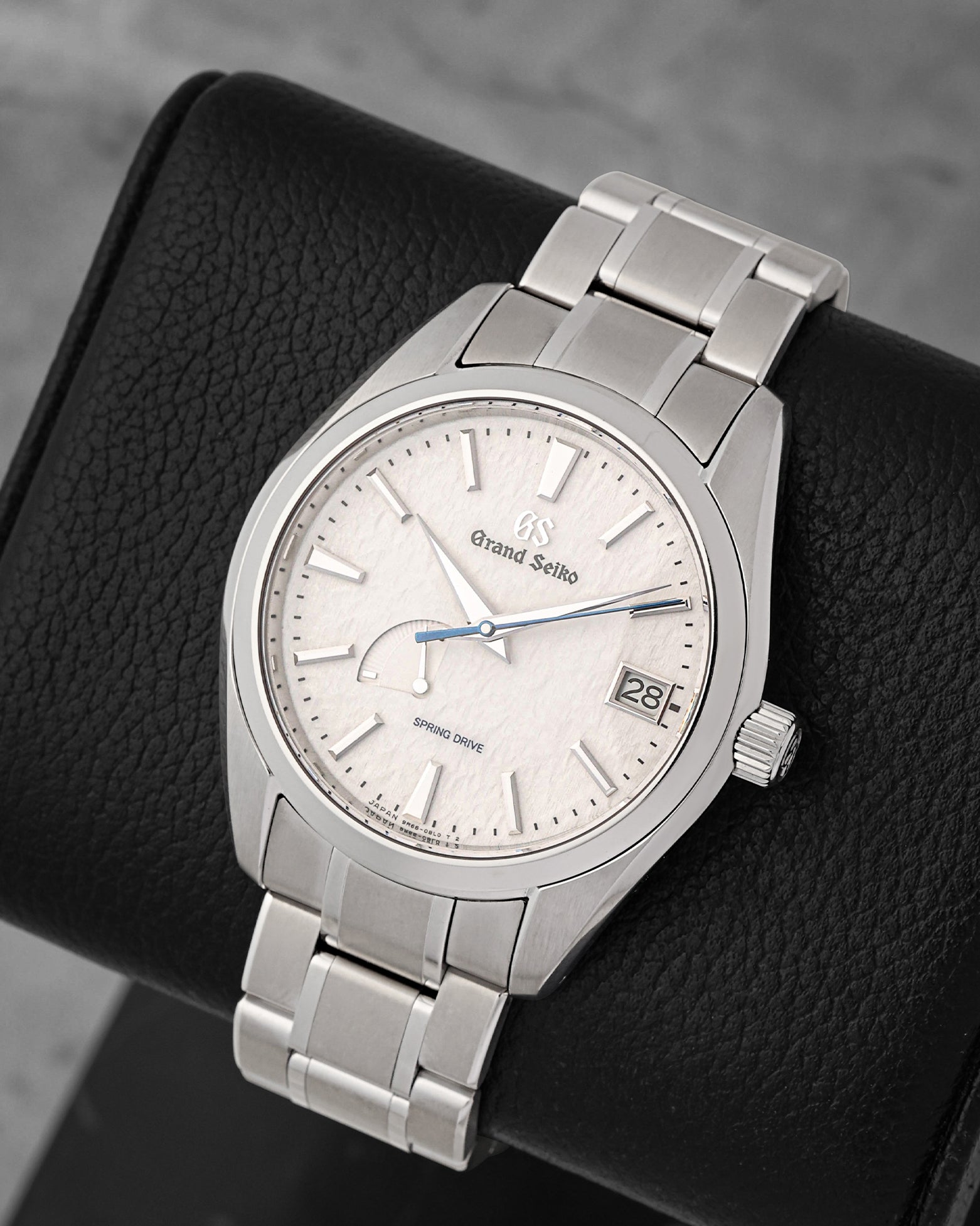A high-angle three-quarter portrait of the 41mm Grand Seiko Snowflake showing the asymmetric power reserve indicator indicator resting on a black leather cushion