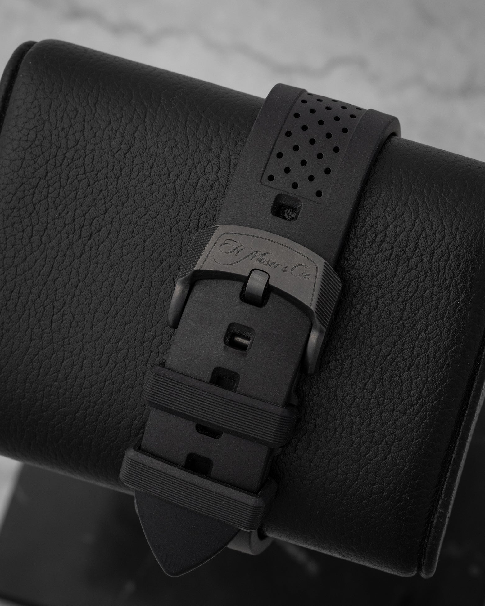 rear snapshot focusing on the ventilated black rubber strap and the black DLC-finished titanium tang buckle engraved with the Moser signature