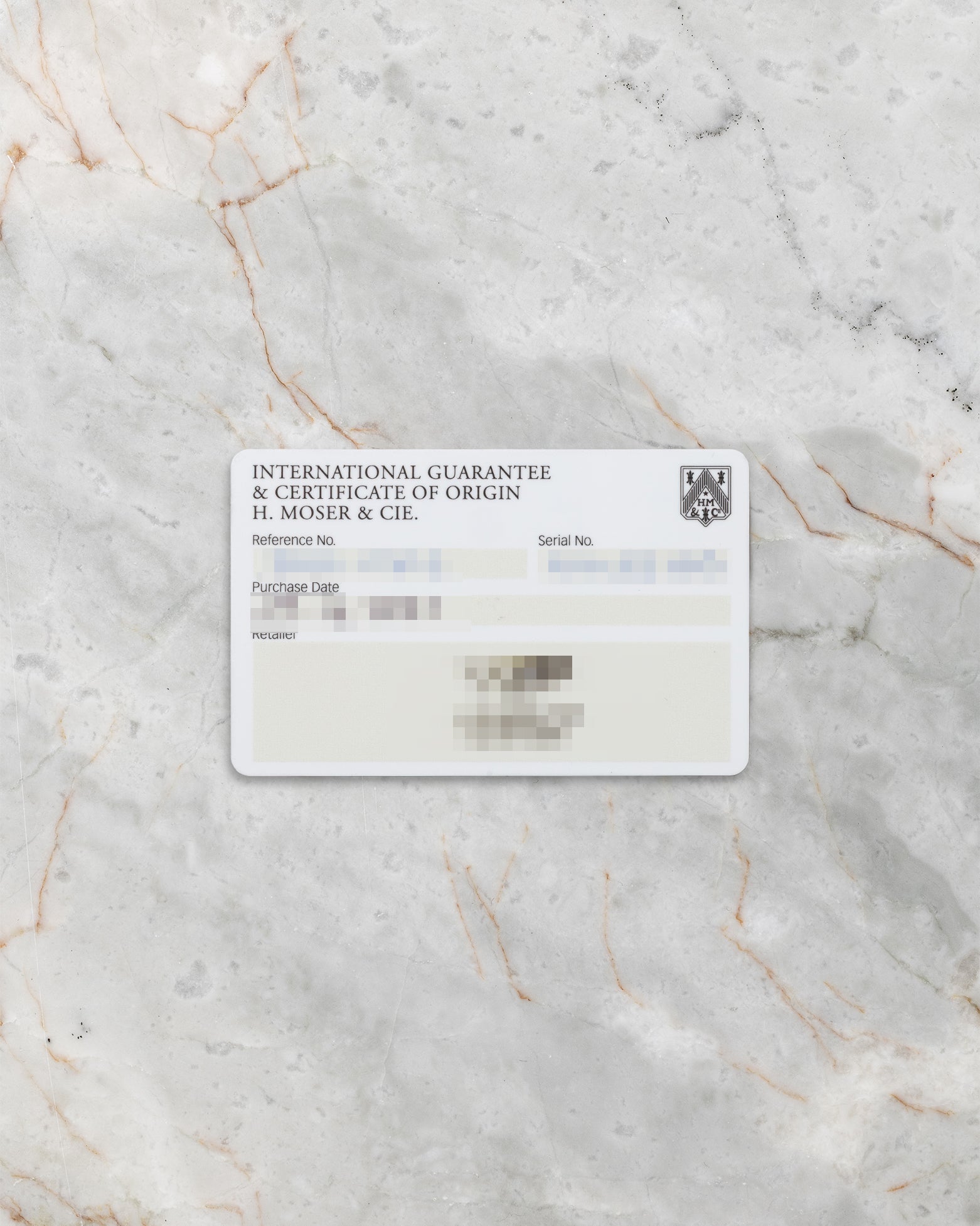 official H. Moser & Cie. international warranty and certificate of origin paper card resting flat on a light gray marble surface