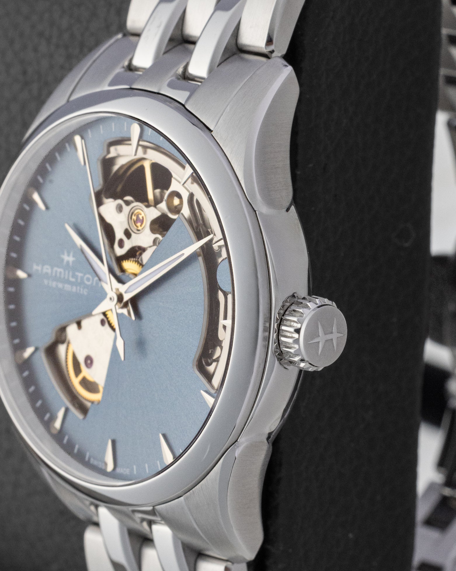 Side profile close-up of a stainless steel Hamilton watch case showing the textured crown with the brand logo