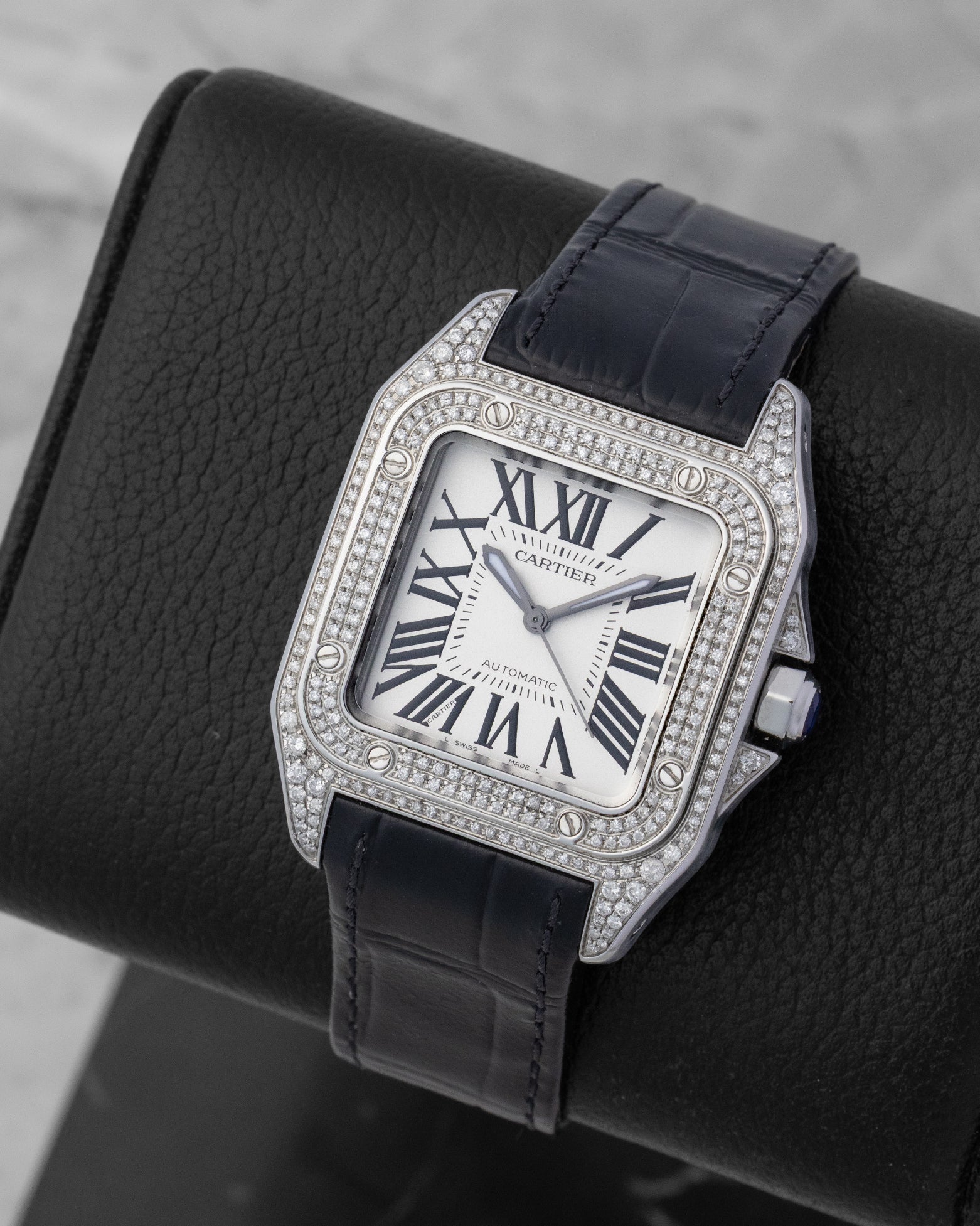 Angled view of an iced-out Cartier Santos 100 watch with pave-set diamonds and the black leather strap