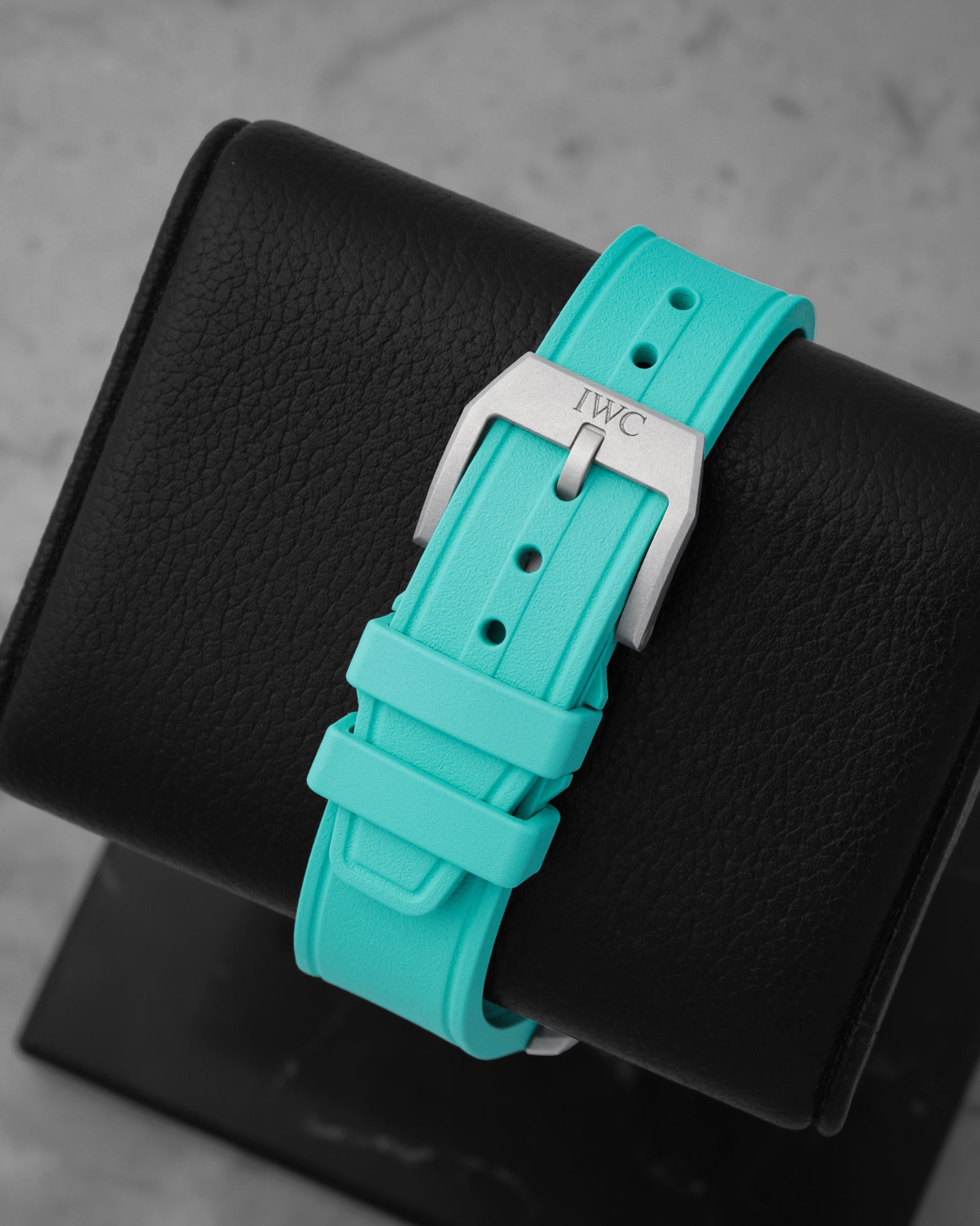 Rear studio view of the textured Petronas green rubber watch strap and the matching sandblasted titanium tang buckle