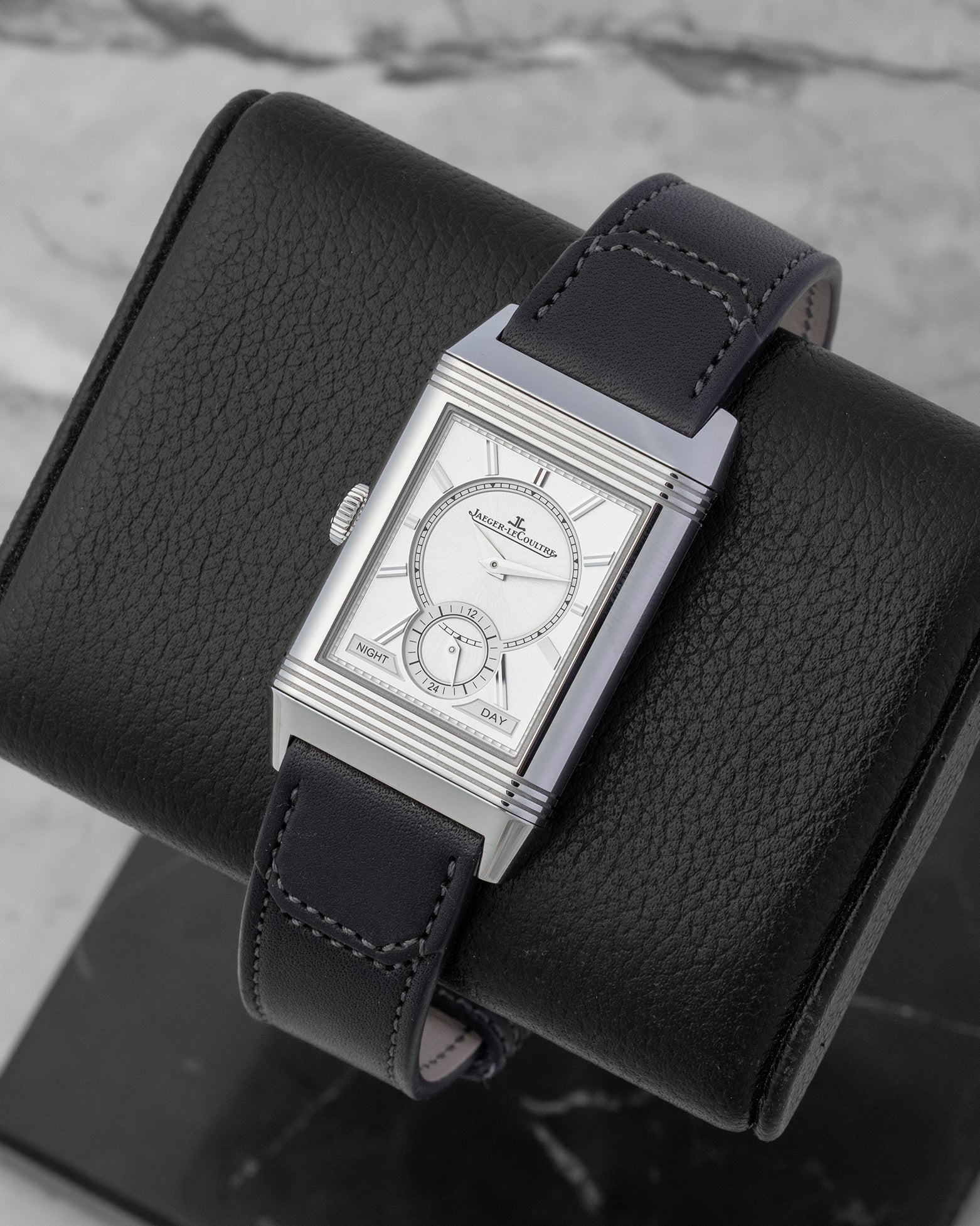 Angled view of a stainless steel Jaeger-LeCoultre Reverso watch on a display stand, highlighting the Art Deco gadroons on the case