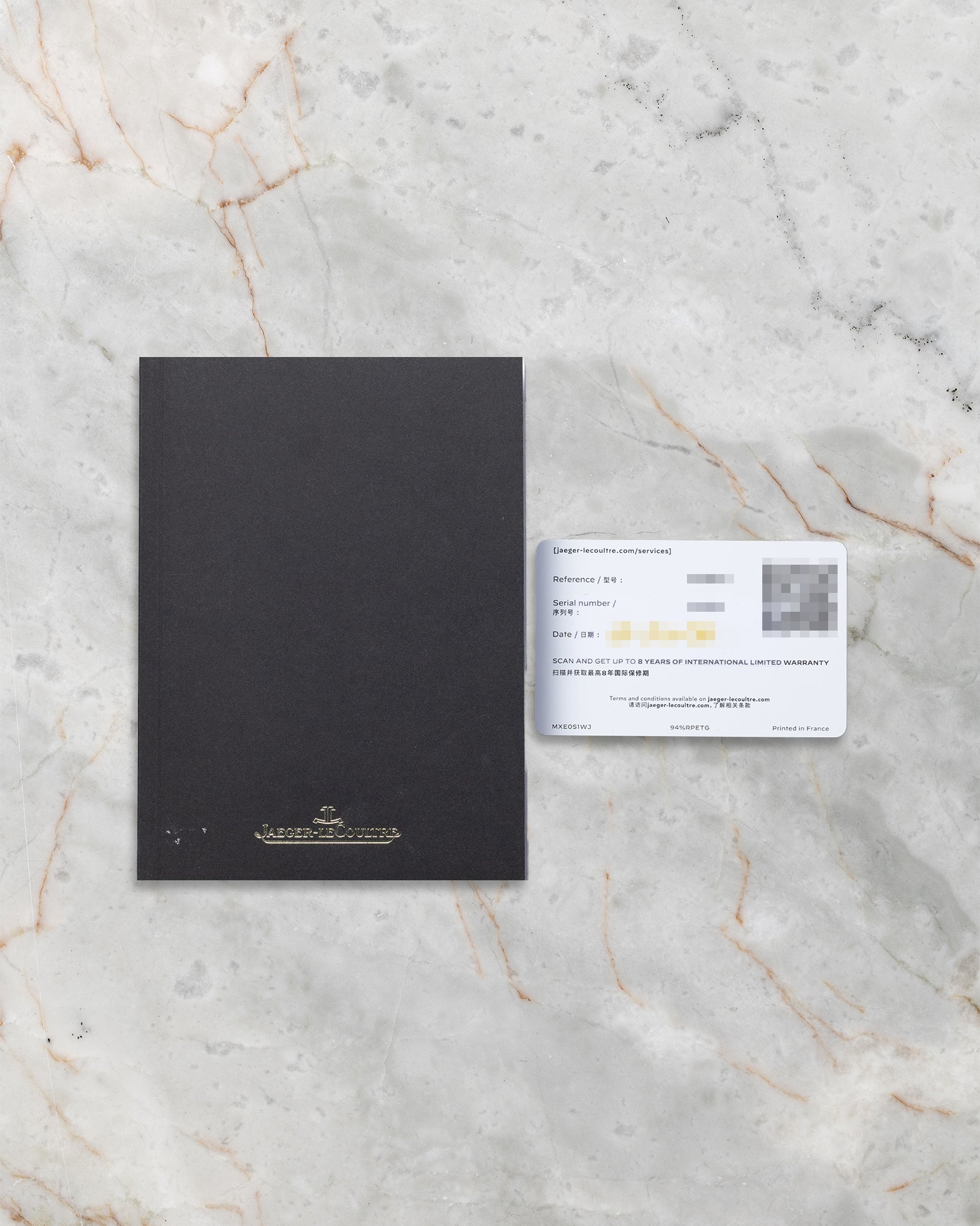 Official Jaeger-LeCoultre international warranty card and user manual booklet on a marble surface