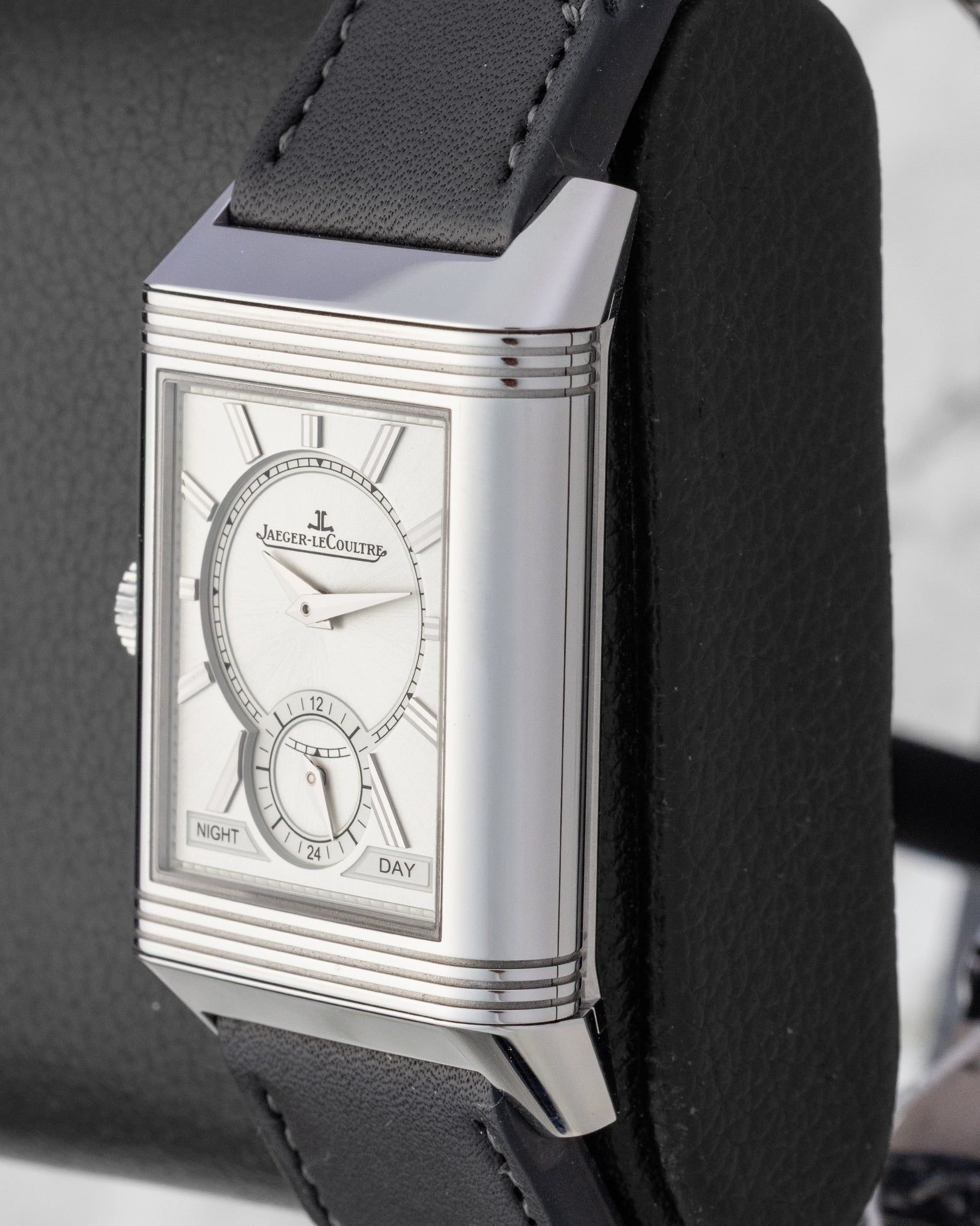 Angled view of a stainless steel Jaeger-LeCoultre Reverso watch on a display stand, highlighting the Art Deco gadroons on the case